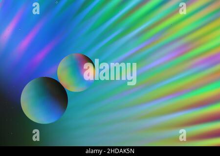 due grandi gocce di olio galleggiano su una superficie d'acqua contro uno sfondo luminoso illuminato, sfondo astratto, primo piano Foto Stock