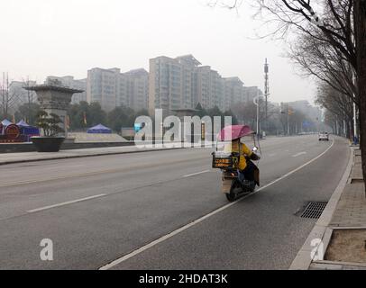 XI'AN, CINA - 5 GENNAIO 2022 - corriere e personale di pulizia in una strada a Xi'an, provincia di Shaanxi, Cina, 5 gennaio 2022. Foto Stock