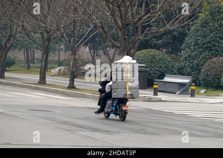 XI'AN, CINA - 5 GENNAIO 2022 - corriere e personale di pulizia in una strada a Xi'an, provincia di Shaanxi, Cina, 5 gennaio 2022. Foto Stock