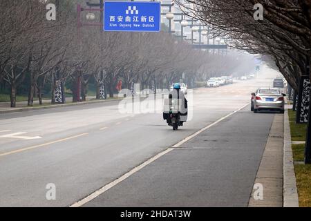 XI'AN, CINA - 5 GENNAIO 2022 - corriere e personale di pulizia in una strada a Xi'an, provincia di Shaanxi, Cina, 5 gennaio 2022. Foto Stock