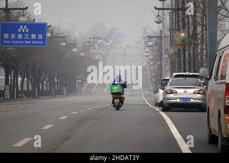 XI'AN, CINA - 5 GENNAIO 2022 - corriere e personale di pulizia in una strada a Xi'an, provincia di Shaanxi, Cina, 5 gennaio 2022. Foto Stock