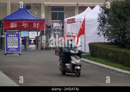 XI'AN, CINA - 5 GENNAIO 2022 - corriere e personale di pulizia in una strada a Xi'an, provincia di Shaanxi, Cina, 5 gennaio 2022. Foto Stock