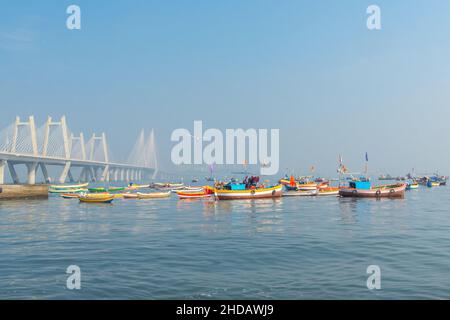 Pescatori tradizionali e colorati Barche di popolazione indigena accanto al moderno ponte 'Sea-link'. Mahim Bay, Mumbai, India. Foto Stock