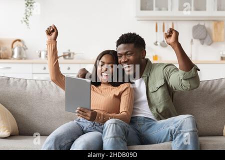 Amanti afroamericani emotivi giocando online giochi su pad Foto Stock