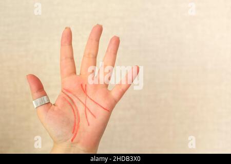 Primo piano della palma femminile con linee di vita disegnate con pennarello rosso isolato su sfondo beige chiaro, spazio di copia per il testo. Palmistry, chiromiccy e. Foto Stock