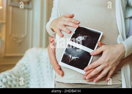 Pianificazione familiare. Scatto corto di amorevole marito che abbraccia la sua moglie incinta tenendo ecografia in mani, uomo e donna in attesa di attesa f Foto Stock