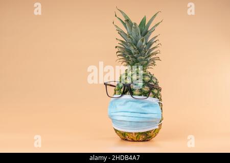 Interpretazione della frutta di ananas in forma umana durante una pandemia con occhiali e una maschera di protezione medico. Spazio di copia Foto Stock