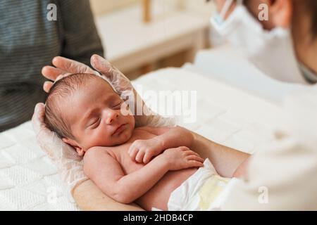 Vista ravvicinata di un medico fisioterapista che tiene un neonato. Foto Stock