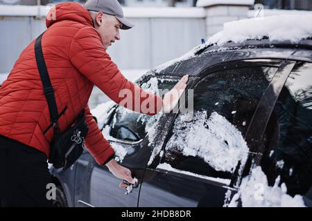 Porta dell'auto congelata. La porta o la serratura dell'automobile è bloccata chiusa. Uomo conducente che cerca di aprire la porta dell'auto congelata o di bloccarla Foto Stock