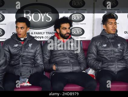 Il Trent Alexander-Arnold di Liverpool, Mo Salah e Roberto Firmino siedono sulla panchina Foto Stock