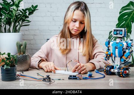 Una ragazza adolescente che collega i cavi ai chip del sensore mentre impara la codifica e la robotica arduino Foto Stock