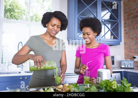 Ragazza felice adolescente e madre che fanno vlog sulla preparazione sana del succo a casa Foto Stock