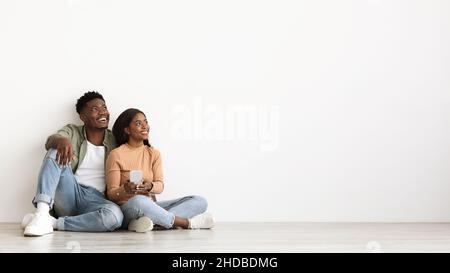 Allegra coppia nera con smartphone che guarda lo spazio per le copie Foto Stock