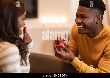 African Man propone di mostrare la casella anello di fidanzamento per la ragazza Indoor Foto Stock