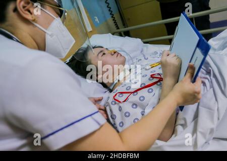 (220105) -- PASIG CITY, 5 gennaio 2022 (Xinhua) -- li Jinxin, una donna cinese di 26 anni, scrive il suo nome assistito dalla sua infermiera Sharricka Mae Navalta all'ospedale Medical City di Pasig City, nelle Filippine, 13 dicembre 2021. Li Jinxin ha trovato il suo sogno di tornare a casa si avverano dopo aver combattuto una malattia devastante per quasi due anni e mezzo nelle Filippine che quasi costano la sua vita. Li ha passato 904 giorni bedridden a Medical City a causa di un'emorragia cerebrale. PER ANDARE CON 'caratteristica: Con l'aiuto dei medici filippini, una volta che la donna cinese criticamente-malata torna a casa' (Xinhua/Rouelle Umali) Foto Stock