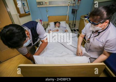 (220105) -- PASIG CITY, 5 gennaio 2022 (Xinhua) -- i lavoratori infermieristi si prendono cura di li Jinxin, una donna cinese di 26 anni, all'ospedale Medical City di Pasig City, nelle Filippine, 13 dicembre 2021. Li Jinxin ha trovato il suo sogno di tornare a casa si avverano dopo aver combattuto una malattia devastante per quasi due anni e mezzo nelle Filippine che quasi costano la sua vita. Li ha passato 904 giorni bedridden a Medical City a causa di un'emorragia cerebrale. PER ANDARE CON 'caratteristica: Con l'aiuto dei medici filippini, una volta che la donna cinese criticamente-malata torna a casa' (Xinhua/Rouelle Umali) Foto Stock