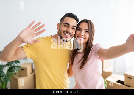 Bella donna caucasica con il marito arabo che prende selfie, trasferendosi insieme a casa nuova Foto Stock