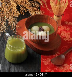 Tangyuan (Tang Yuan, sfere di Dumpling del piatto glutinoso) con zuppa verde dolce dello sciroppo di tè in una ciotola su sfondo della tavola di legno per Solstice di inverno o Lanter Foto Stock