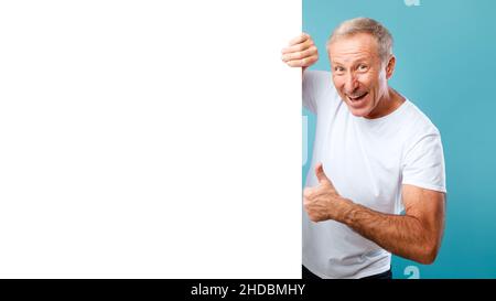 Uomo maturo che sbirciava fuori bianco bianco pubblicità cartellone mostrando come Foto Stock