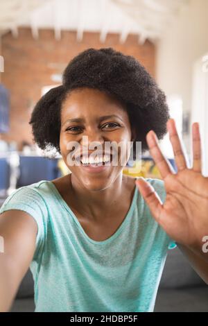 Ritratto di felice donna afroamericana che sventolano la mano sulla videochiamata a casa Foto Stock