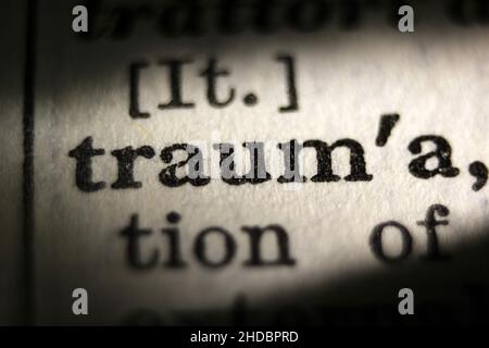 Parola 'trauma' stampata sulla pagina del libro, macro close-up Foto Stock