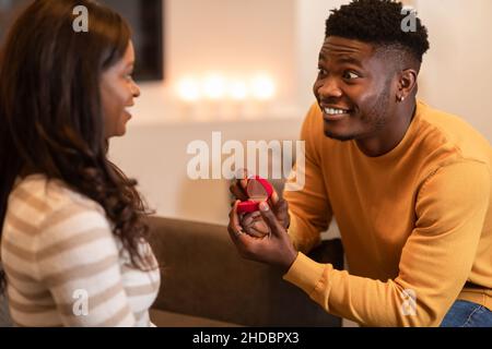 Black Man propone di aprire la scatola che mostra Woman Engagement Ring Indoor Foto Stock