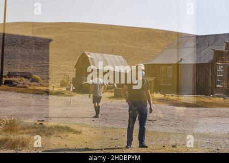 Bridgeport, California, Stati Uniti. 16 ottobre 2020. I turisti mascherati si sono riflessi su una vetrata del Bodie state Historic Park, durante le pandemie del 19. Bodie Foto Stock