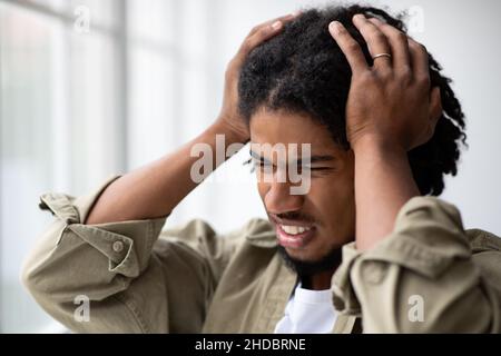 Disturbi mentali. Ritratto di sollecitato ansioso giovane africano americano uomo toccare testa Foto Stock