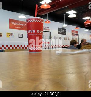 Cinque Guys Burgers e Fries bevono una tazza su un tavolo all'interno del ristorante dell'hamburger; una tazza di bibite rosse o bibite analcoliche con paglia. Foto Stock
