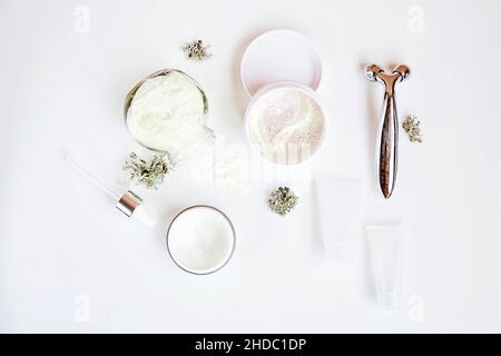 Cosmetici per la cura del viso benessere impostati su sfondo bianco gradiente. Maschera di alginato e patch trasparenti. Crema e massaggiatore. Muschio naturale. Ialuronico e cosmetico idratante. Prodotti per dermatologia. Foto Stock