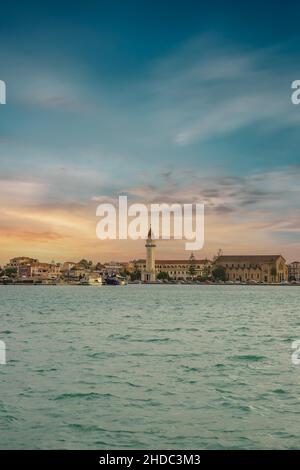 Vista al tramonto sul mare verso una città mediterranea. Chiesa di San Dionisio, isola di Zante, Grecia Foto Stock