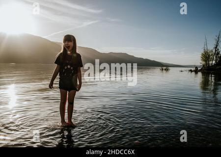 Ragazza felice che gioca in lago in giorno di sole Foto Stock