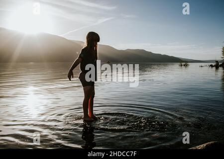 Giovane ragazza che si tuffa in un lago in una giornata di sole Foto Stock