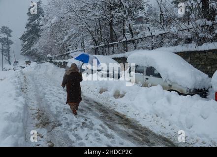 Srinagar, India. 5th Jan 2022. Una donna del Kashmiri cammina oltre il veicolo sepolto sotto la neve durante la nevicata pesante si accumula a Tangmarg, ad ovest di Srinagar Kashmir. L'autostrada nazionale di Srinagar-Jammu, l'unico collegamento stradale che collega la Valle con il resto del mondo, è stata chiusa per il traffico, mentre nove voli sono stati cancellati anche a causa delle condizioni meteorologiche avverse a Jammu e Kashmir come nevicata pesante continuato per il secondo giorno dritto il Mercoledì. (Credit Image: © Sajad Hameed/Pacific Press via ZUMA Press Wire) Foto Stock