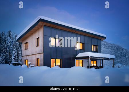 Casa solare clima-neutro con riscaldamento autosufficiente e sostenibile e preparazione di acqua calda di notte in inverno nevoso Foto Stock