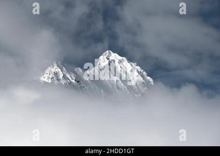 Le vette innevate della montagna sporgono dalla zuppa di nebbia con un gradiente bianco verso il basso Foto Stock