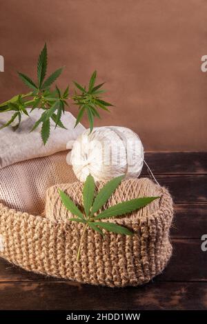 Vari tipi di prodotti in fibra di canapa. Fili di canapa, filati e tessuti con foglie di canapa su sfondo ligneo. Foto Stock