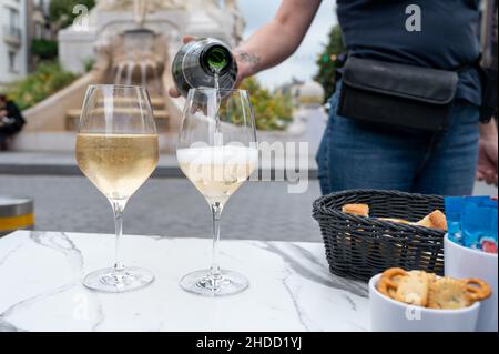 Cameriere giovane versare di champagne brut spumante in bicchieri in Street cafe nel centro storico della città di Reims, Champagne, Francia Foto Stock