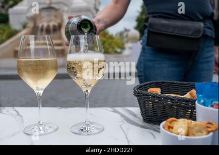 Cameriere giovane versare di champagne brut spumante in bicchieri in Street cafe nel centro storico della città di Reims, Champagne, Francia Foto Stock