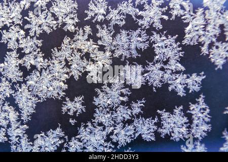 Motivo di gelo naturale sulla finestra di vetro da vicino con sfondo scuro Foto Stock