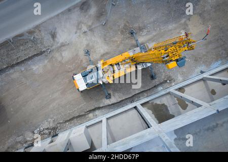 Vista dall'alto su una gru per autocarri pesanti di grandi dimensioni di fronte a ponteggi in calcestruzzo di un locale industriale Foto Stock