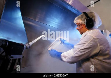 Austin Texas USA, 1994: High TECH Clean Room: Impiegato in 'Bunny Suit' mira a spruzzare CO2 cristalli pressurizzati sui componenti del computer all'interno di High-tec Foto Stock