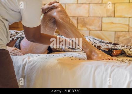 La giovane donna riceve un massaggio scrub nel salone termale Foto Stock