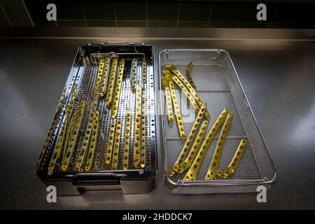 le piastre in titanio color oro per il trattamento delle fratture femorali sono conservate in un vassoio per strumenti Foto Stock