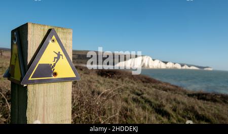 Segno giallo e nero di avvertimento del pericolo di erosione sul bordo della scogliera che domina Seven Sisters a Hope Gap, eaford nel Sussex orientale, Regno Unito. Foto Stock