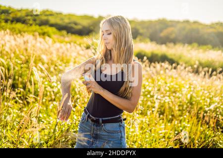 Repellente per zanzare. Insetti spray anti insetti per virus zika. Donna spruzzando repellente insetto mettere sulla pelle all'aperto in natura utilizzando flacone spray Foto Stock