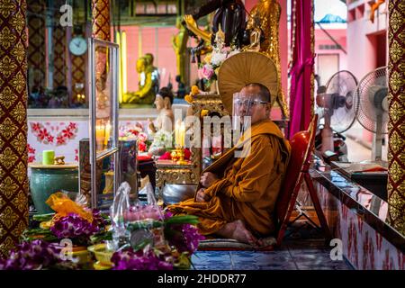 Bangkok, Tailandia. 31st Dic 2021. Il monaco thailandese supervisiona i devoti mentre pregano prima di subire il rituale di resurrezione al tempio. I devoti sono risuscitati in un rituale annuale di Capodanno a Wat Takien vicino a Nonthaburi. Questo rito inizia con una preghiera seguita dai partecipanti che cantano con santi fili avvolti intorno alla testa prima di stendersi in una bara per “morire” e essere purificati. Credit: SOPA Images Limited/Alamy Live News Foto Stock