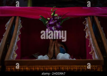 Bangkok, Tailandia. 31st Dic 2021. La donna tailandese si deposita in una bara durante il rituale di resurrezione al tempio.i devoti sono resuscitati in un rituale annuale di Capodanno a Wat Takien vicino a Nonthaburi. Questo rito inizia con una preghiera seguita dai partecipanti che cantano con santi fili avvolti intorno alla testa prima di stendersi in una bara per “morire” e essere purificati. Credit: SOPA Images Limited/Alamy Live News Foto Stock