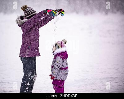 Lago Louise, Canada - Dicembre 23 2021: Ragazze palpando neve sul lago Louise ghiacciato Foto Stock