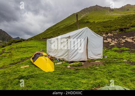 Tenda e una barca in una valle vicino al passo Ala Kul in Kirghizistan Foto Stock